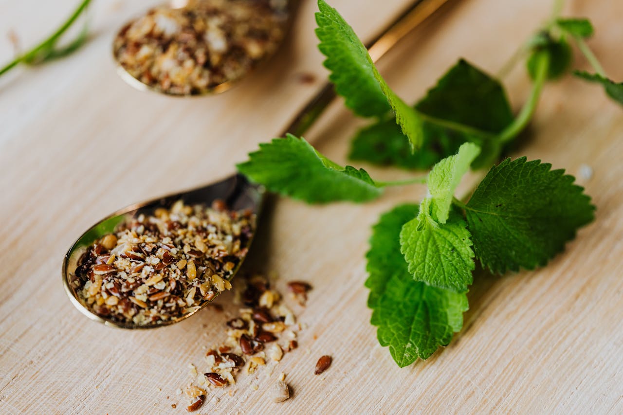 pexels-photo-4871161 Mint leaves and mixed spices in spoons on a wooden surface, perfect for culinary enthusiasts.